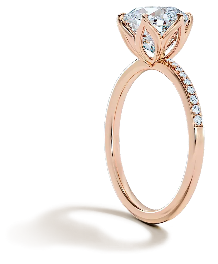 Side view of a rose gold engagement ring featuring a round diamond, pavΓ© band, and elegant floral-style setting