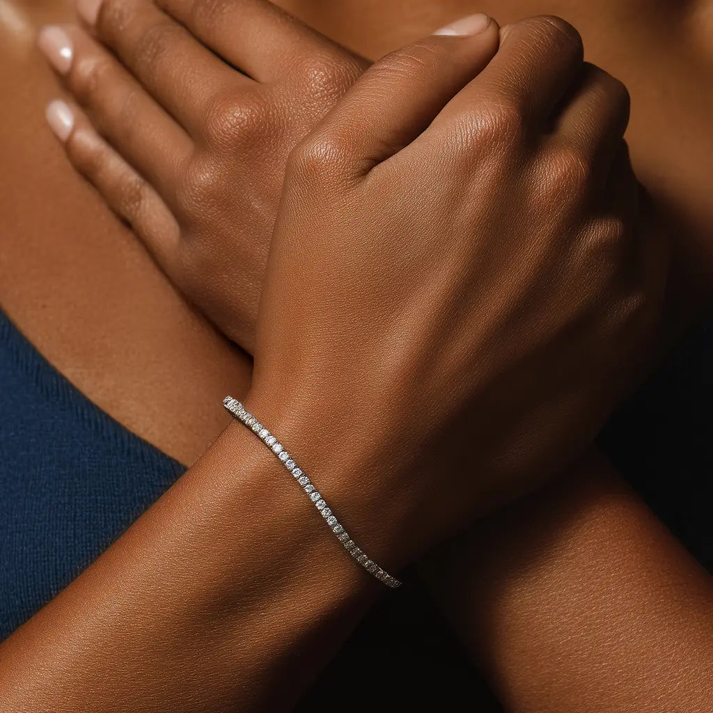 Woman wearing a delicate 3 carat white gold diamond tennis bracelet, arms crossed near her chest.