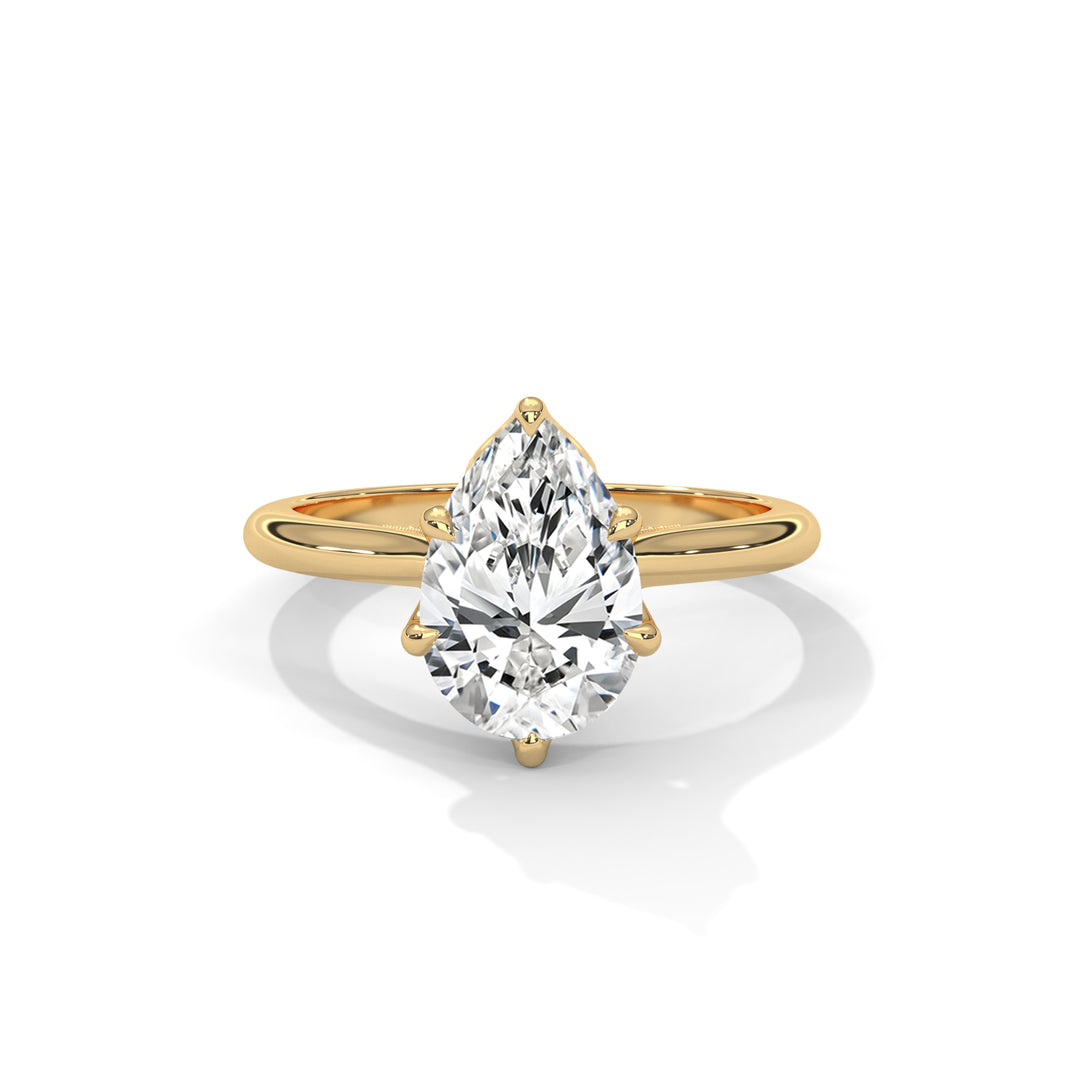 Gold ring with a pear-shaped diamond on a white background
