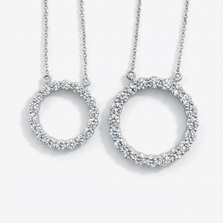 Two silver circular pendants on chains against a white background