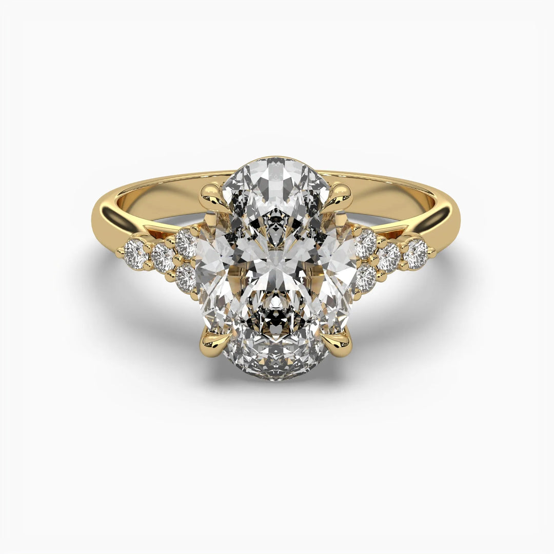 Gold ring with an oval center diamond flanked by smaller diamonds on a white background.