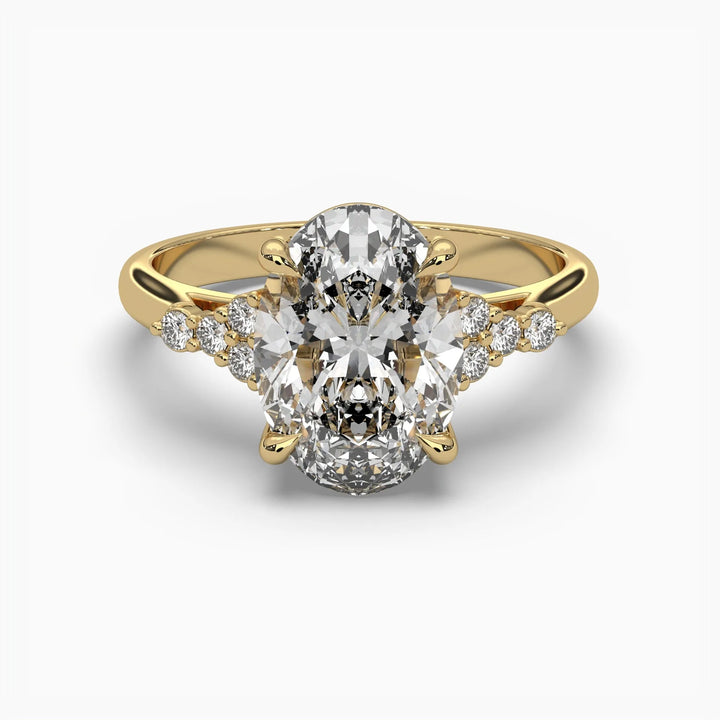 Gold ring with an oval center diamond flanked by smaller diamonds on a white background.