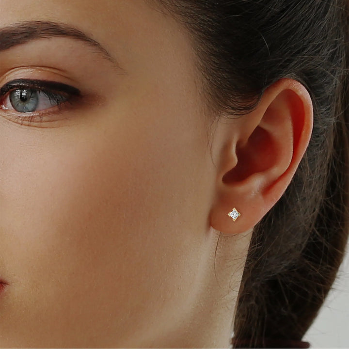 Close up of an ear with a diamond earring, partial view of dark hair.