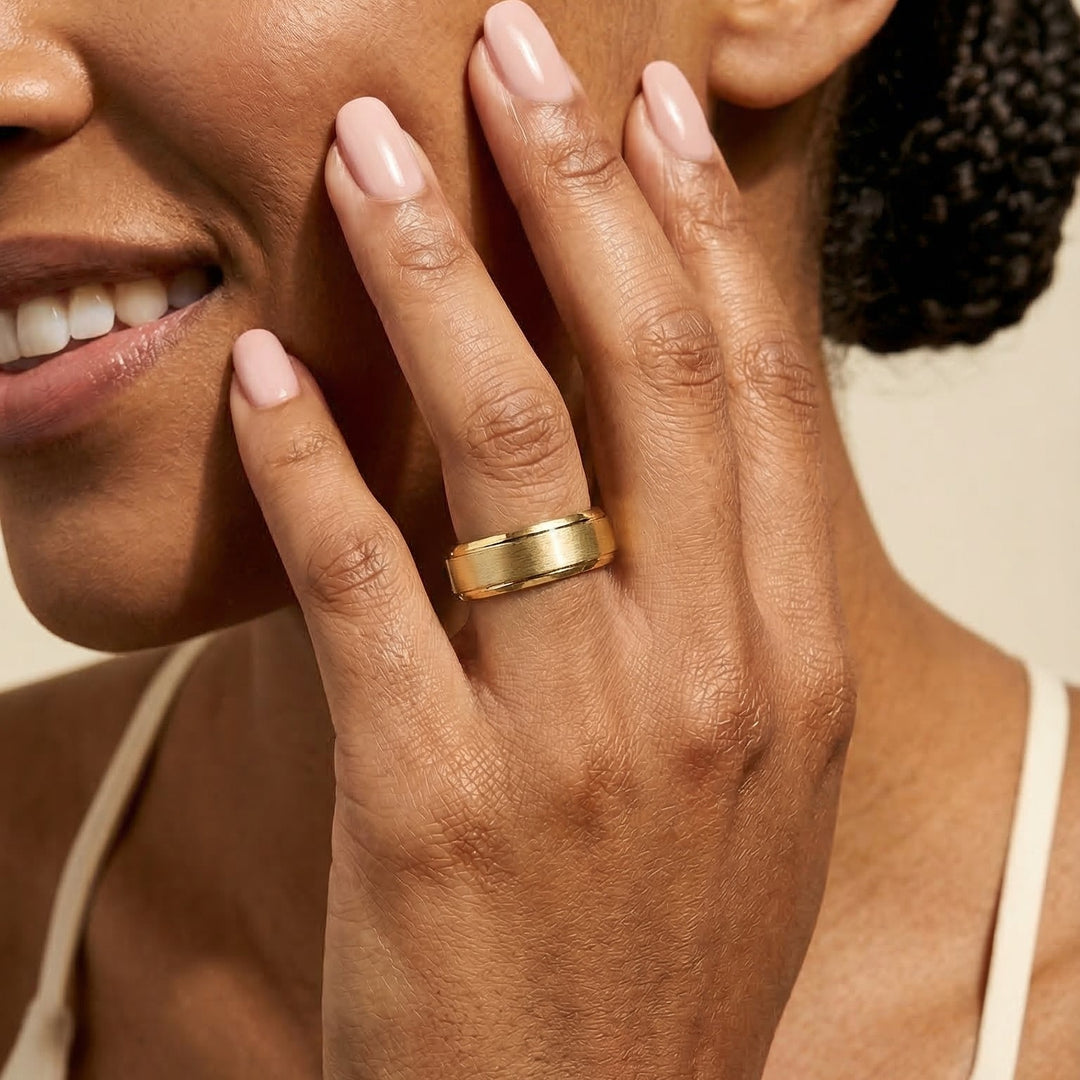 Close-up of a hand with a gold ring on a neutral background
