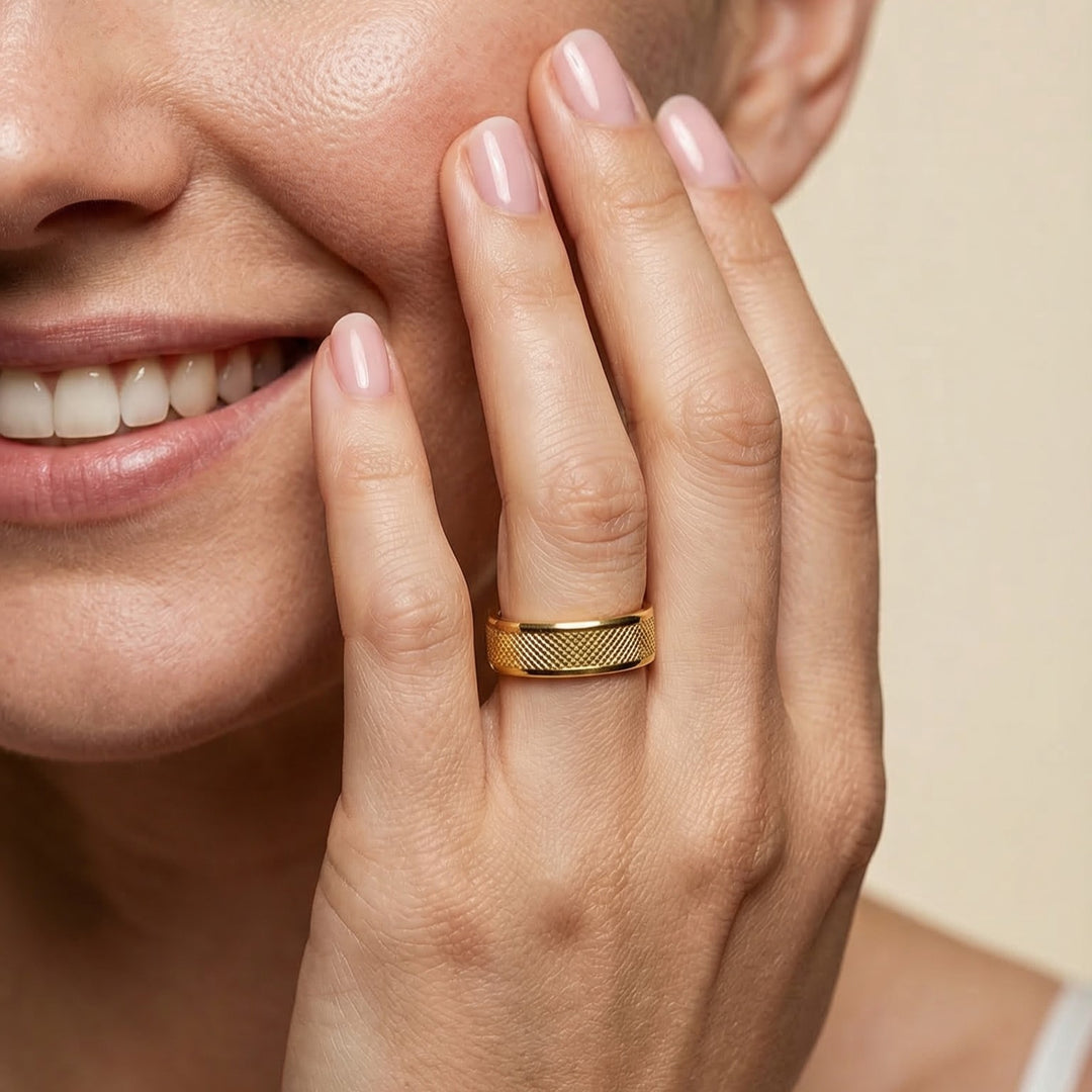 Close-up of a woman's hand with a gold ring on her finger, touching her face.
