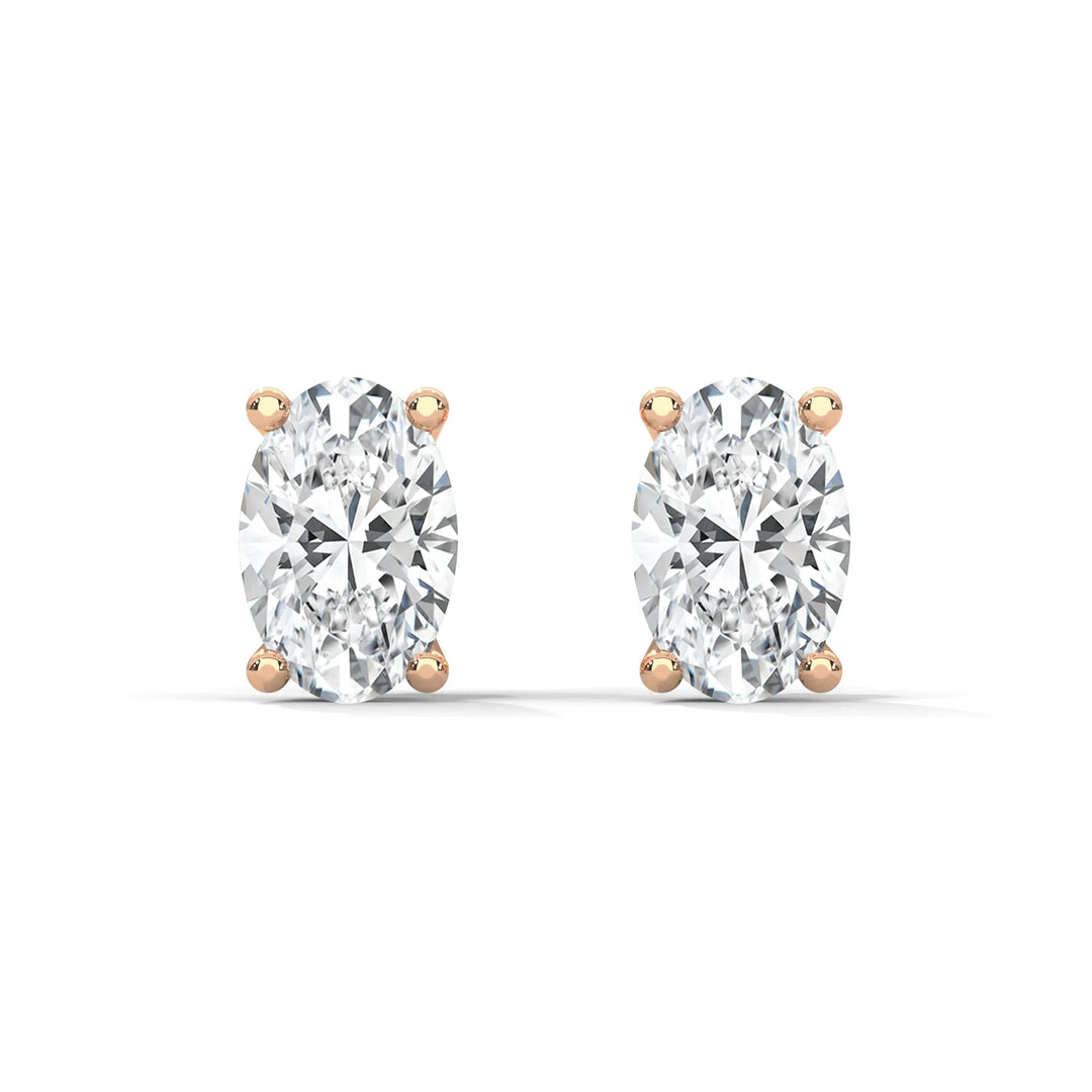 A pair of oval cut diamond stud earrings with rose gold settings on a white background.