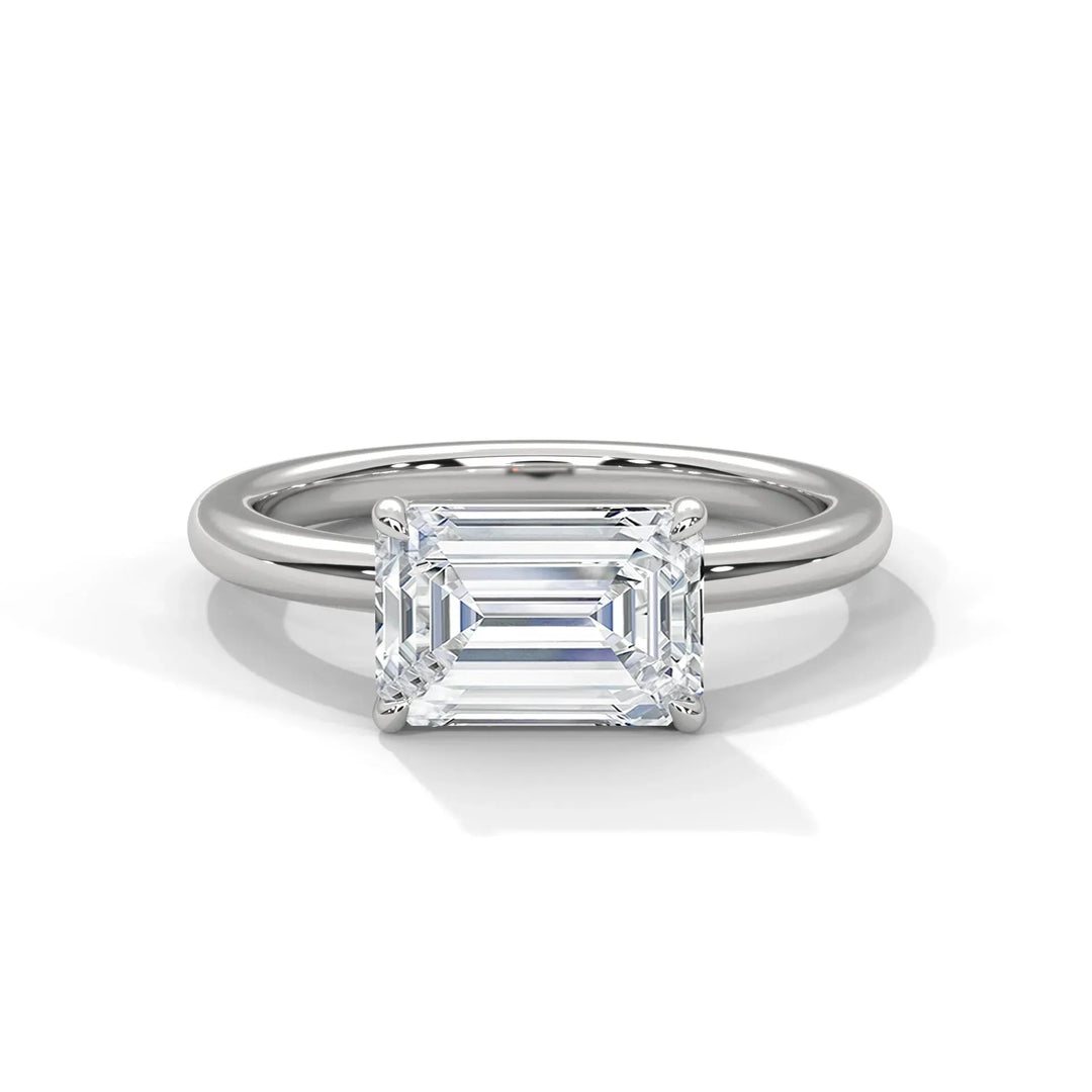 Elegant engagement ring with a rectangular emerald-cut diamond on a sleek silver band, highlighting its lustrous and sophisticated design.