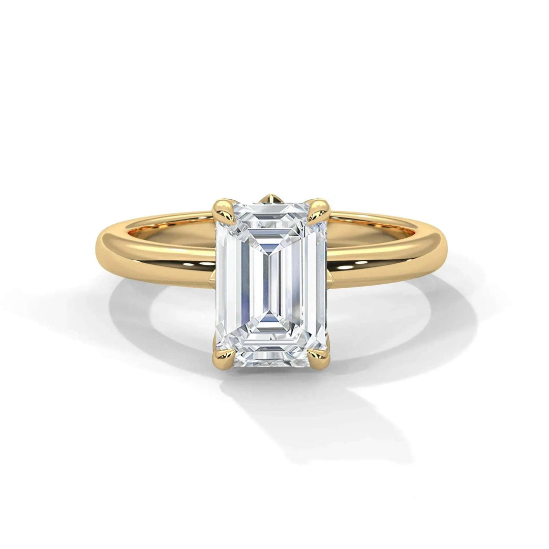 An elegant gold ring featuring a large, rectangular emerald-cut diamond set in four prongs. The band is smooth, conveying a sense of luxury and sophistication.