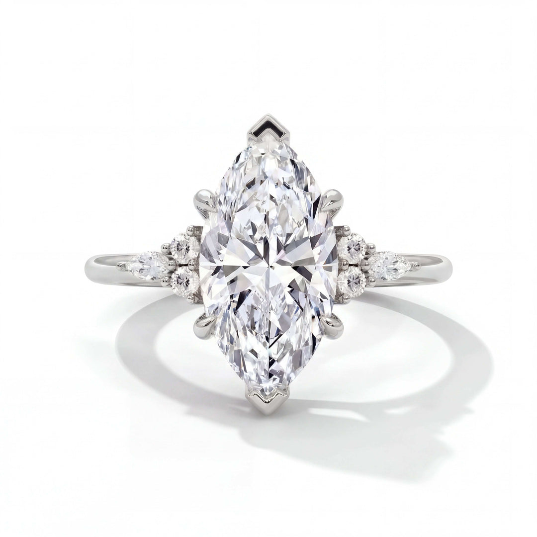 Elegant marquise-cut diamond ring with a central stone flanked by smaller round diamonds on a delicate silver band, set against a white background.