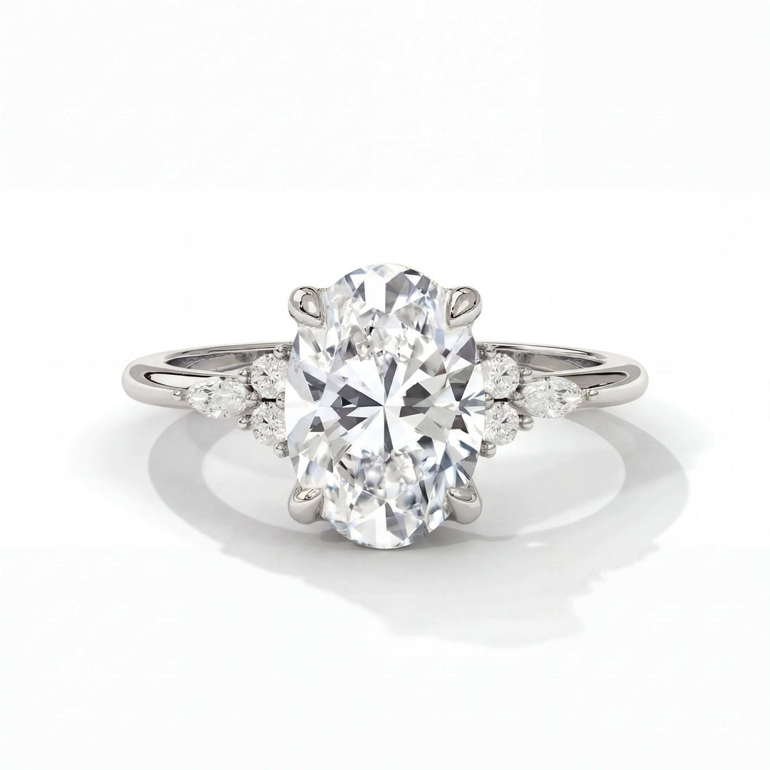 Elegant oval-cut diamond ring with a sparkling centerpiece, flanked by two pear-shaped and two round diamonds on a sleek silver band, exuding luxury.