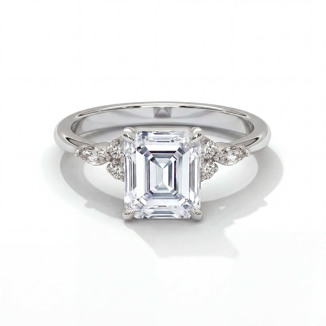 Elegant ring featuring an emerald-cut diamond at the center, flanked by smaller round and marquise diamonds on a polished silver band, exuding luxury.