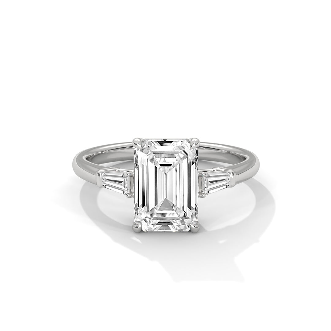 Elegant ring featuring an emerald-cut diamond, flanked by tapered baguette diamonds, set in a shiny platinum band; conveys luxury and sophistication.