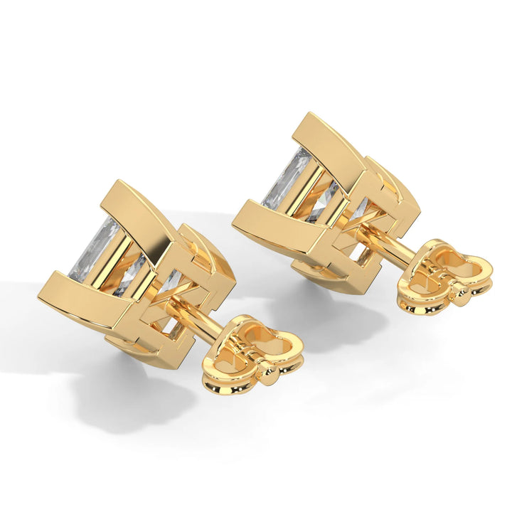 Gold cufflinks with rectangular clear stones on a white surface.