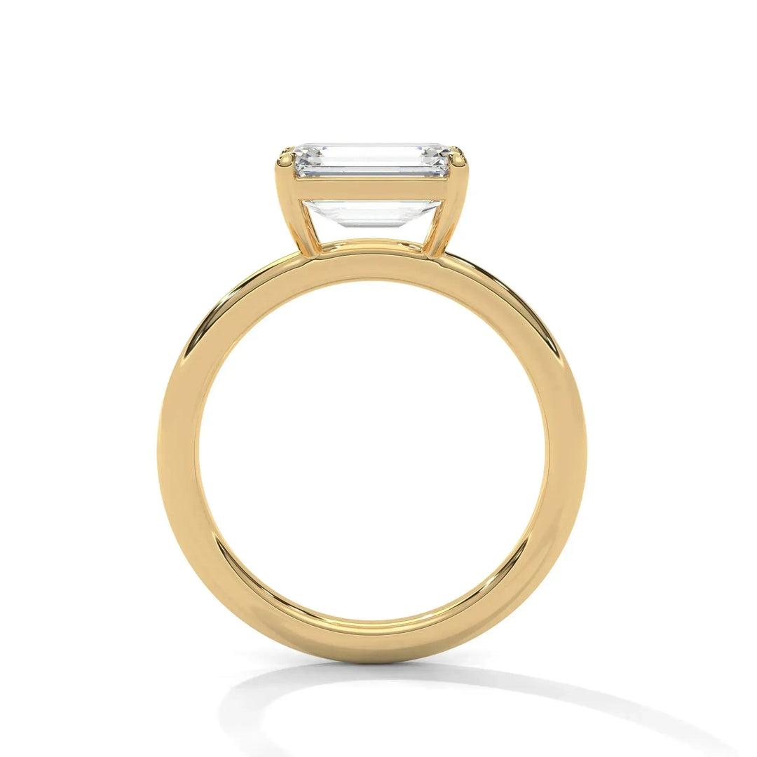 Gold engagement ring with an emerald-cut diamond set in a sleek, elegant band. The diamond is elevated, showcasing a modern and sophisticated design.