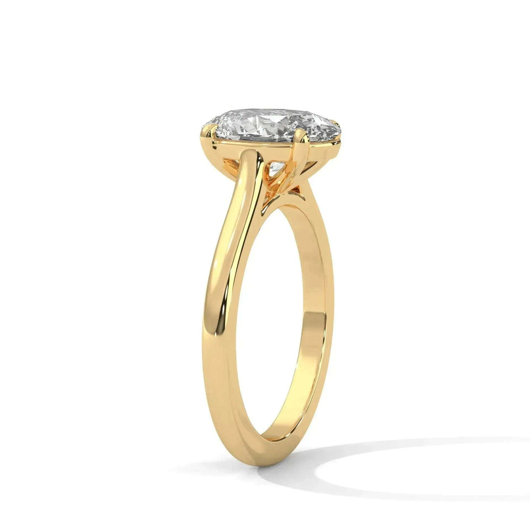 A gold engagement ring features an elegant, slender band with a large, sparkling diamond set in a four-prong mount. The design feels timeless and sophisticated.