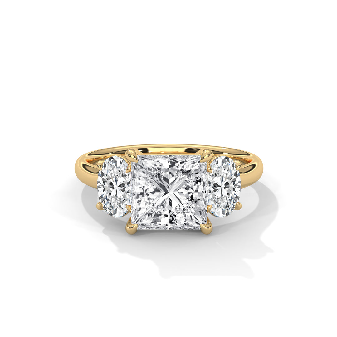 A gold engagement ring features a large princess-cut diamond in the center, flanked by two oval diamonds, set against a white background.