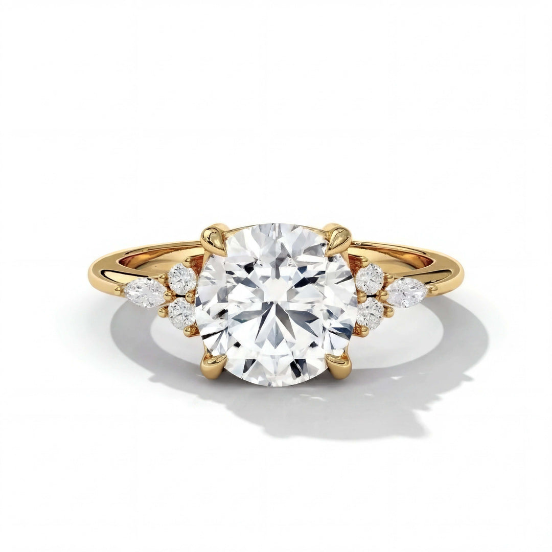 A gold engagement ring features a large round diamond at its center, accented with smaller side diamonds. The overall effect is elegant and luxurious.