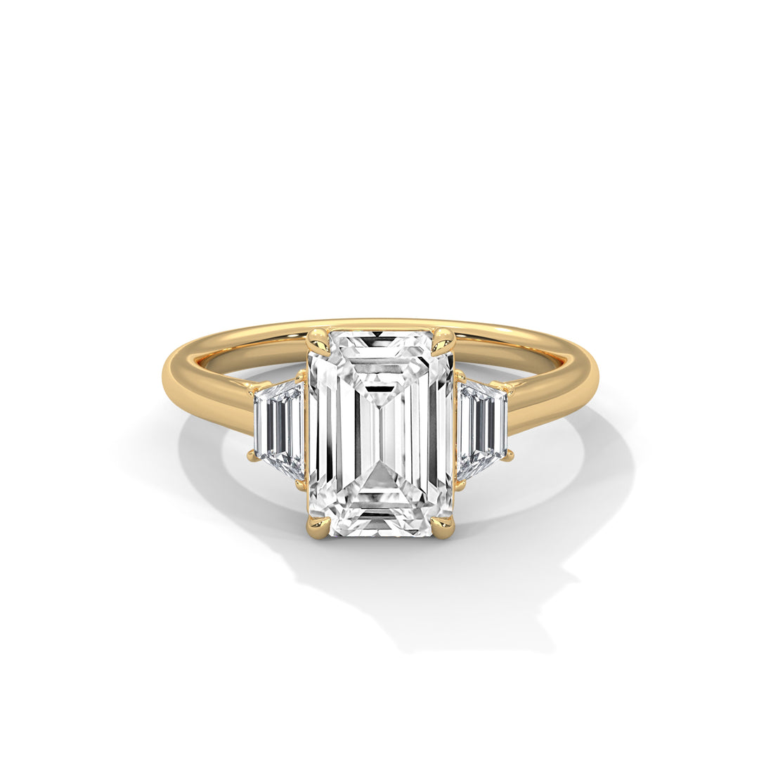 A gold engagement ring featuring a central emerald-cut diamond flanked by two smaller baguette-cut diamonds, evoking elegance and luxury.