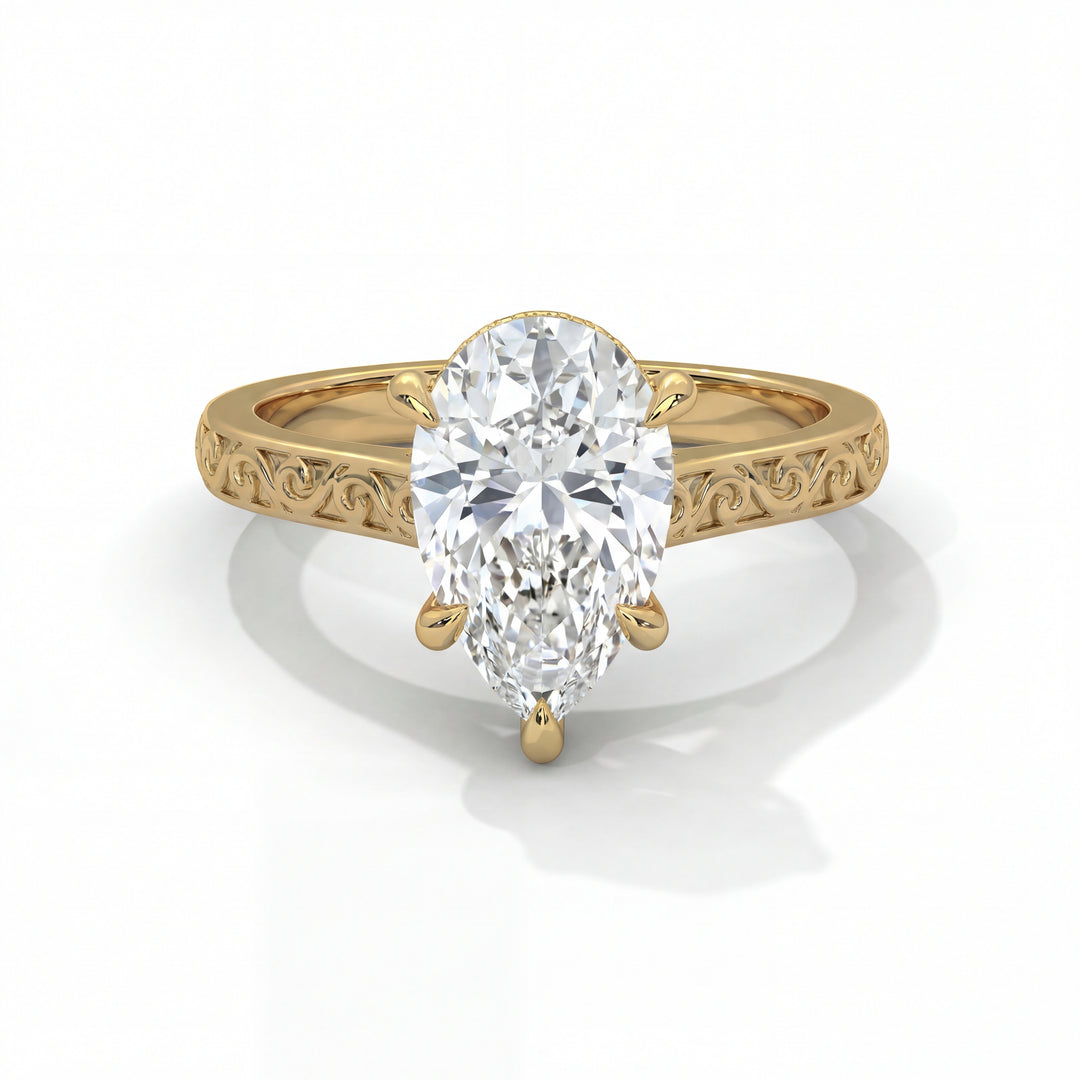 Gold engagement ring with a large pear-shaped diamond. The band features ornate swirls, adding elegance and sophistication, set against a white background.