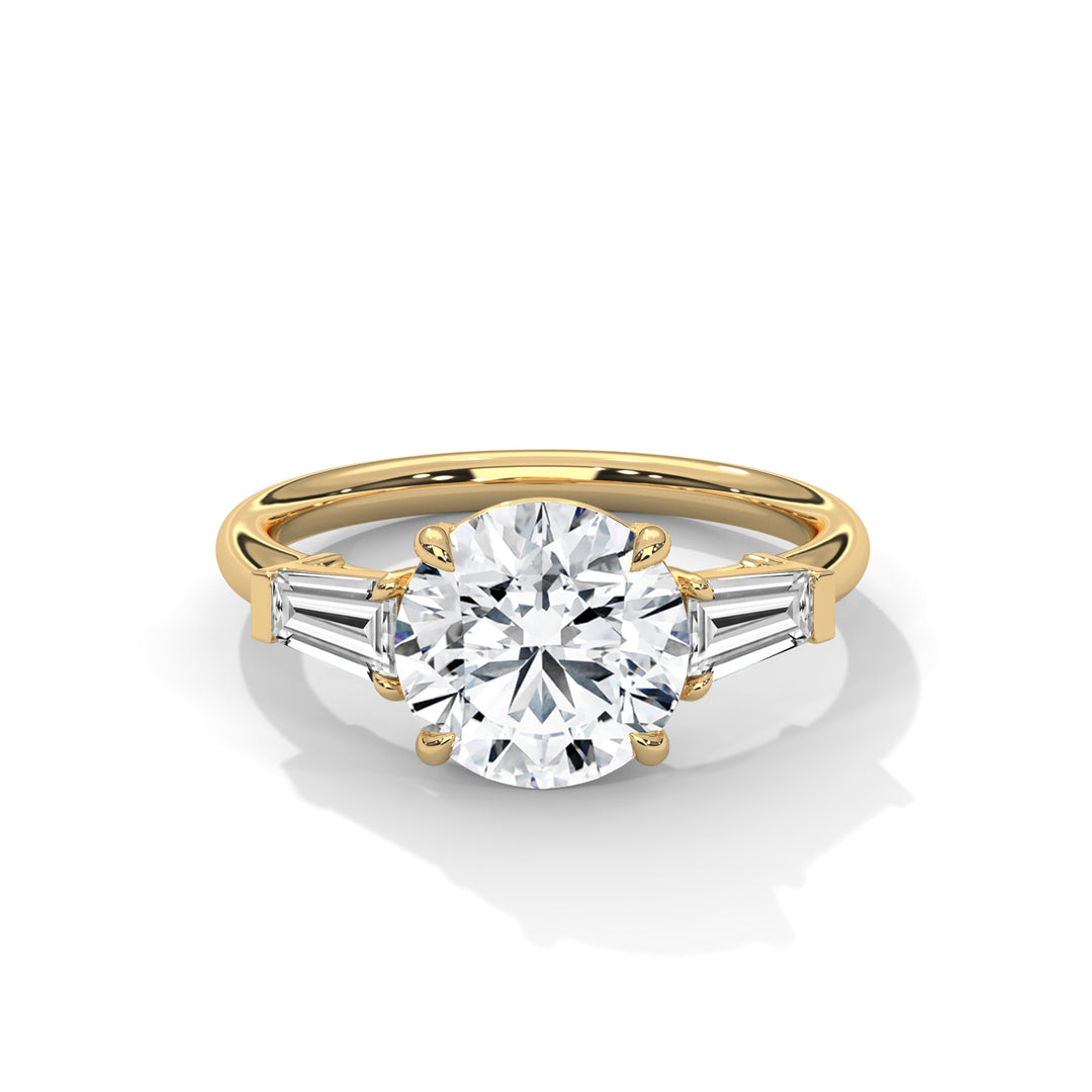 A gold engagement ring with a large round diamond in the center, flanked by two tapered baguette diamonds on either side, reflecting elegance and luxury.