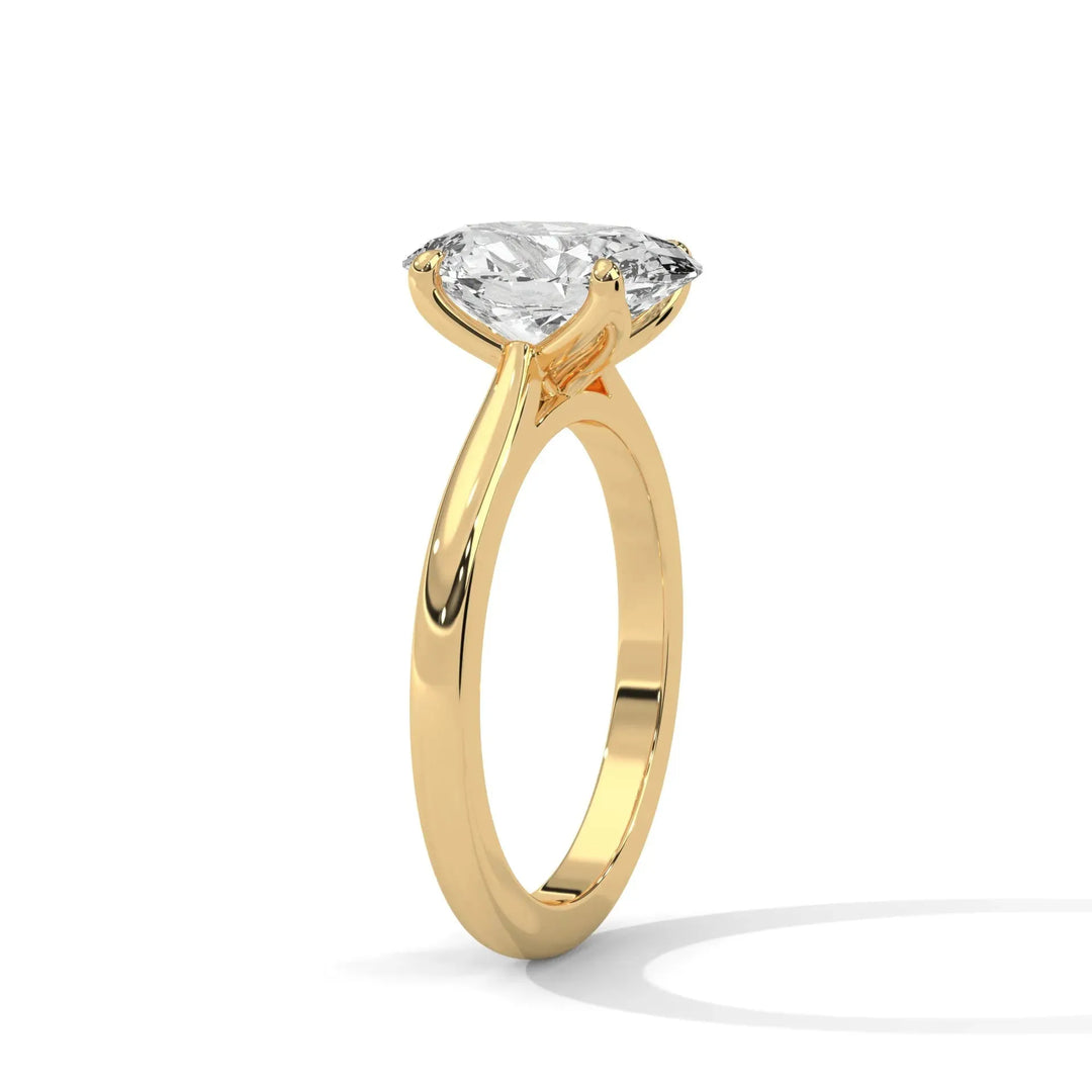 A gold engagement ring with a large round diamond in a prong setting. The ring's smooth band and gem reflect light, creating an elegant, luxurious look.