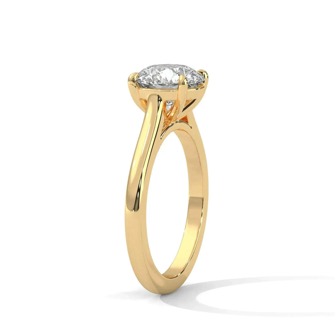 A gold engagement ring with a sparkling round diamond set in a minimalist prong setting, casting a soft shadow on a plain white background.