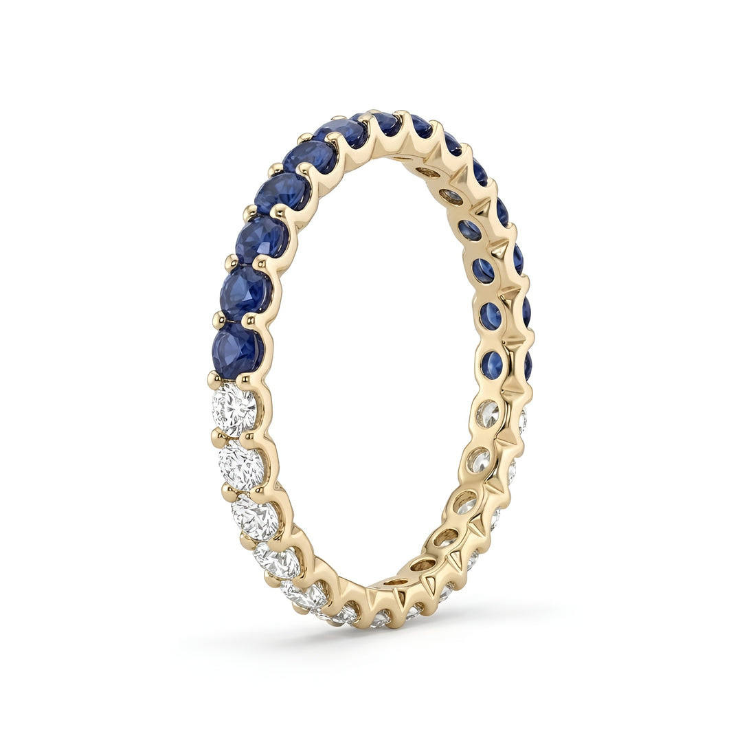 A gold eternity ring is adorned with alternating blue sapphires and white diamonds. The ring's delicate design conveys elegance and sophistication.