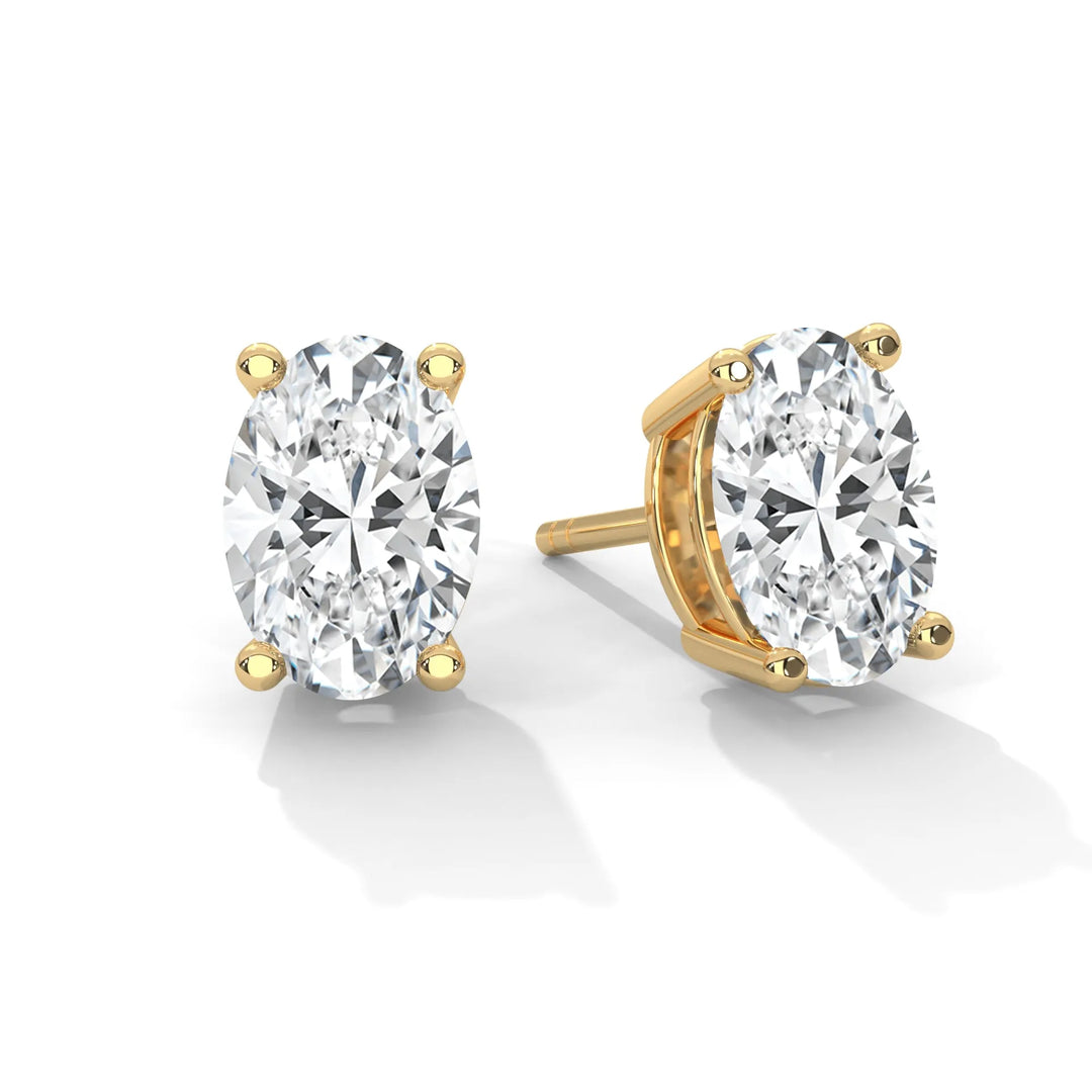 Gold oval cut diamond stud earrings on a white background.