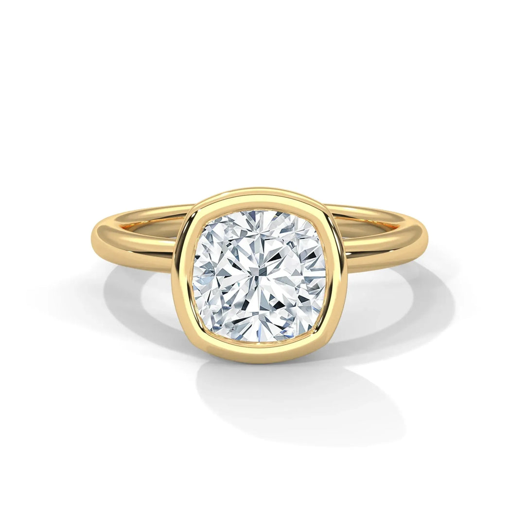 A gold ring with a cushion-cut diamond solitaire in a bezel setting. The ring's simple yet elegant design conveys luxury and timeless sophistication.