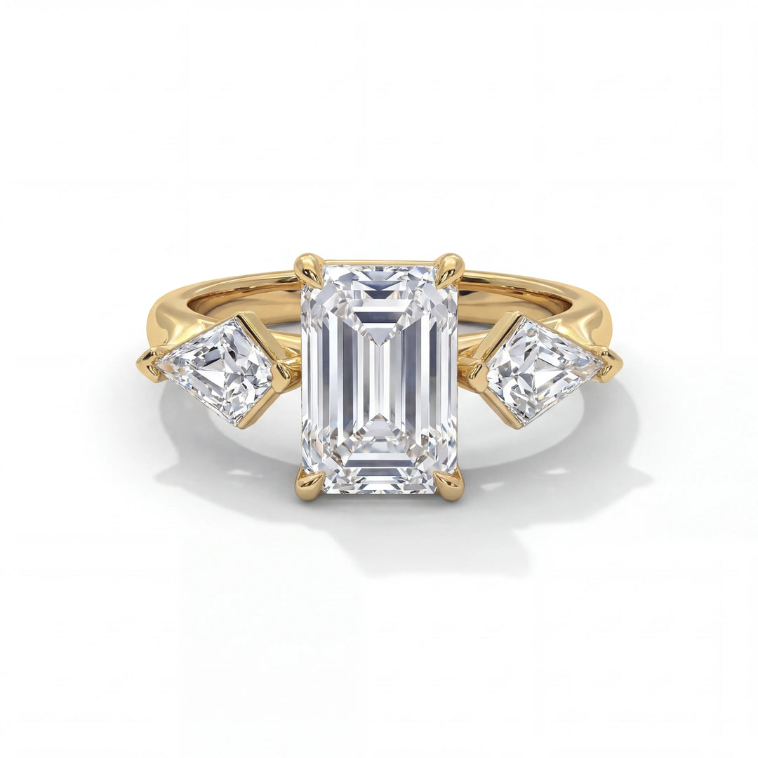 Gold ring with an emerald-cut center diamond flanked by two smaller trapezoid diamonds, all in prong settings, against a white background. Elegant and luxurious.