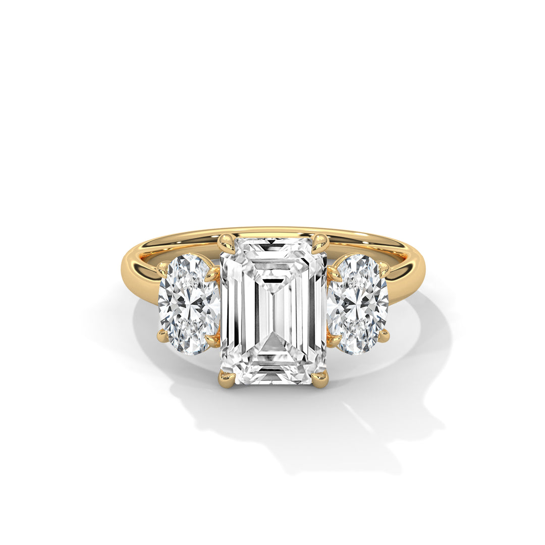 A gold ring with an emerald-cut central diamond flanked by two oval diamonds, set in a three-stone design. The image conveys elegance and luxury.