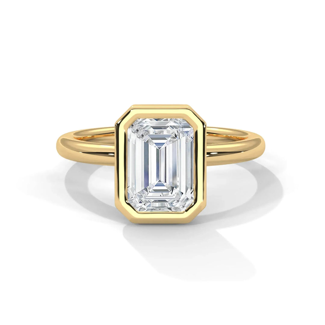 A gold ring with an emerald-cut diamond in a bezel setting. The diamond's geometric facets and yellow gold band convey elegance and sophistication.