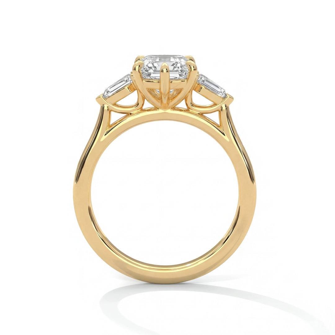 A gold ring with an emerald-cut diamond center stone and two smaller side diamonds in prong settings. The elegant design conveys luxury and sophistication.