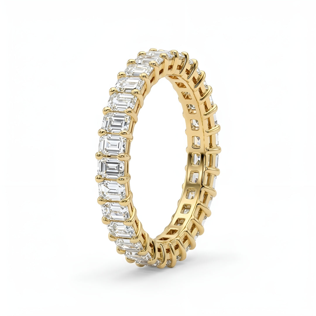 Gold ring with emerald-cut diamonds on a white background