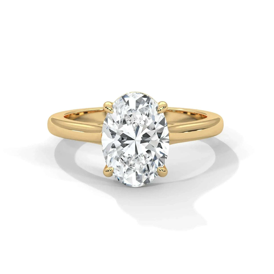 A gold ring featuring an oval-cut diamond in a prong setting. The band is shiny and smooth, with the diamond reflecting light, conveying elegance and luxury.