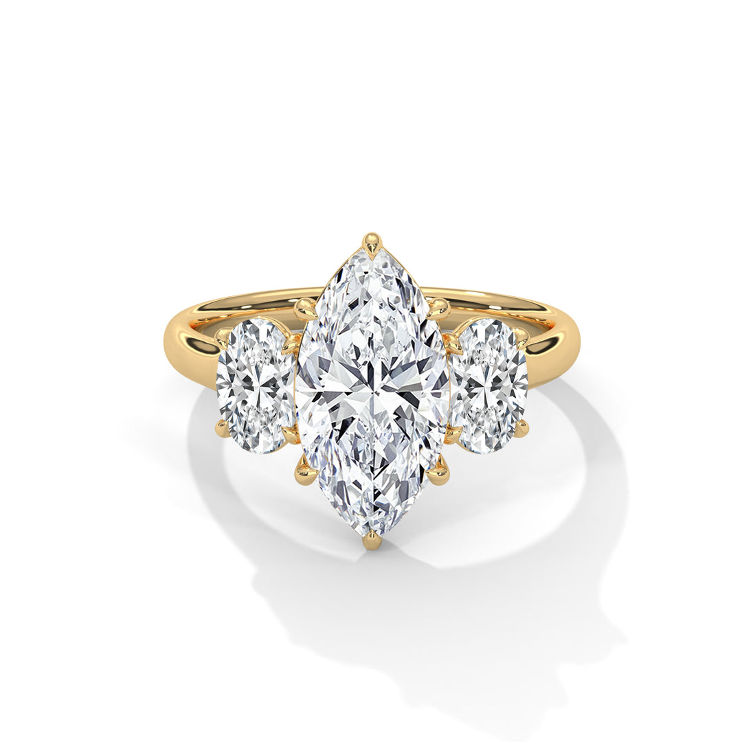 Gold ring with a large marquise-cut diamond flanked by two oval-cut diamonds on each side, casting a shadow on a white background.