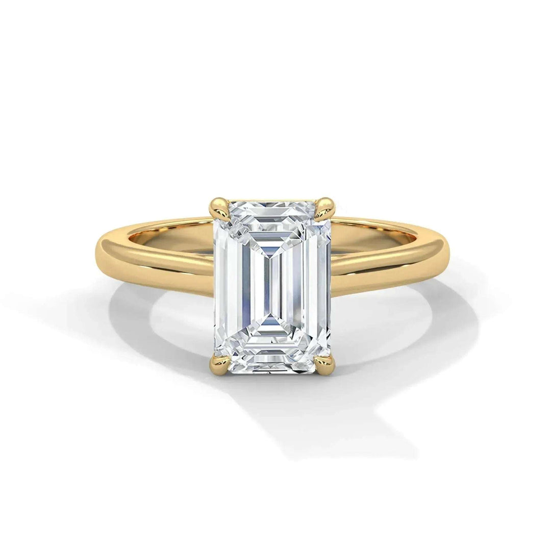 Gold ring with a large rectangular emerald-cut diamond solitaire set in four prongs on a white background.