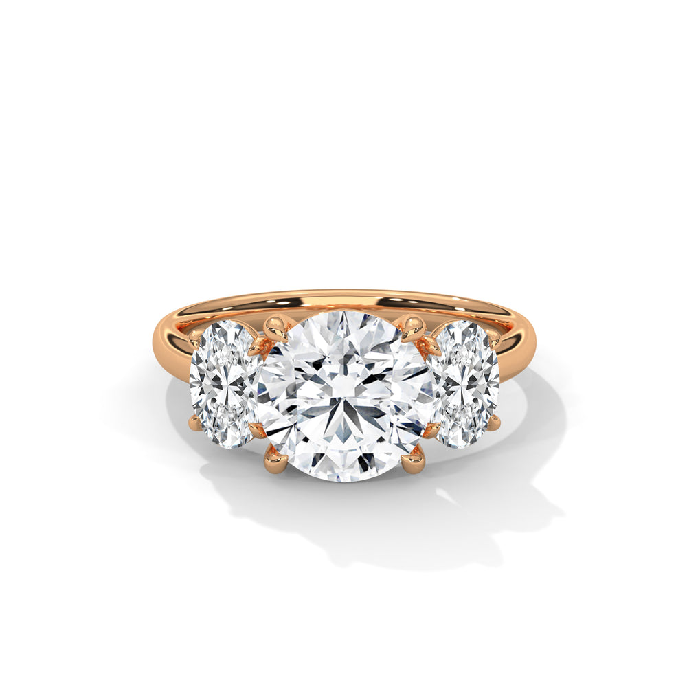A gold ring with a large, round center diamond flanked by two smaller diamonds. The setting is elegant and luxurious, capturing light beautifully.