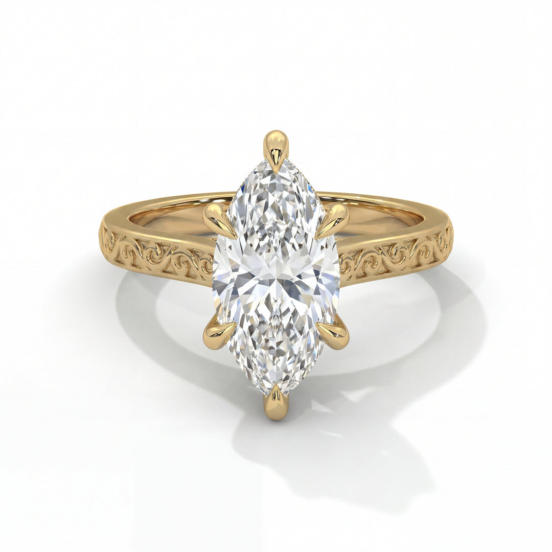 Gold ring with a marquise-cut diamond set in an ornate band featuring intricate scrollwork. The design is elegant and sophisticated, exuding luxury.