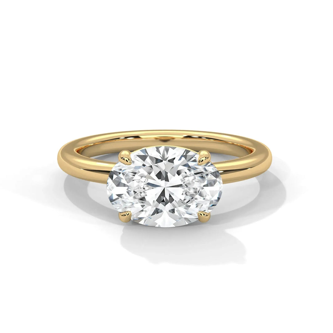 A gold ring with an oval-cut diamond centerpiece held by four prongs, reflecting light. The background is white, emphasizing elegance and luxury.