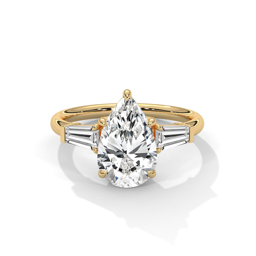 A gold ring with a pear-shaped diamond centerpiece flanked by two baguette diamonds on each side, reflecting elegance and luxury against a plain backdrop.