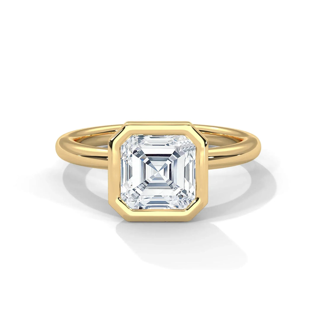 A gold ring with a square-cut diamond set in a bezel, showcasing a modern and elegant design. The diamond sparkles against the smooth gold band.