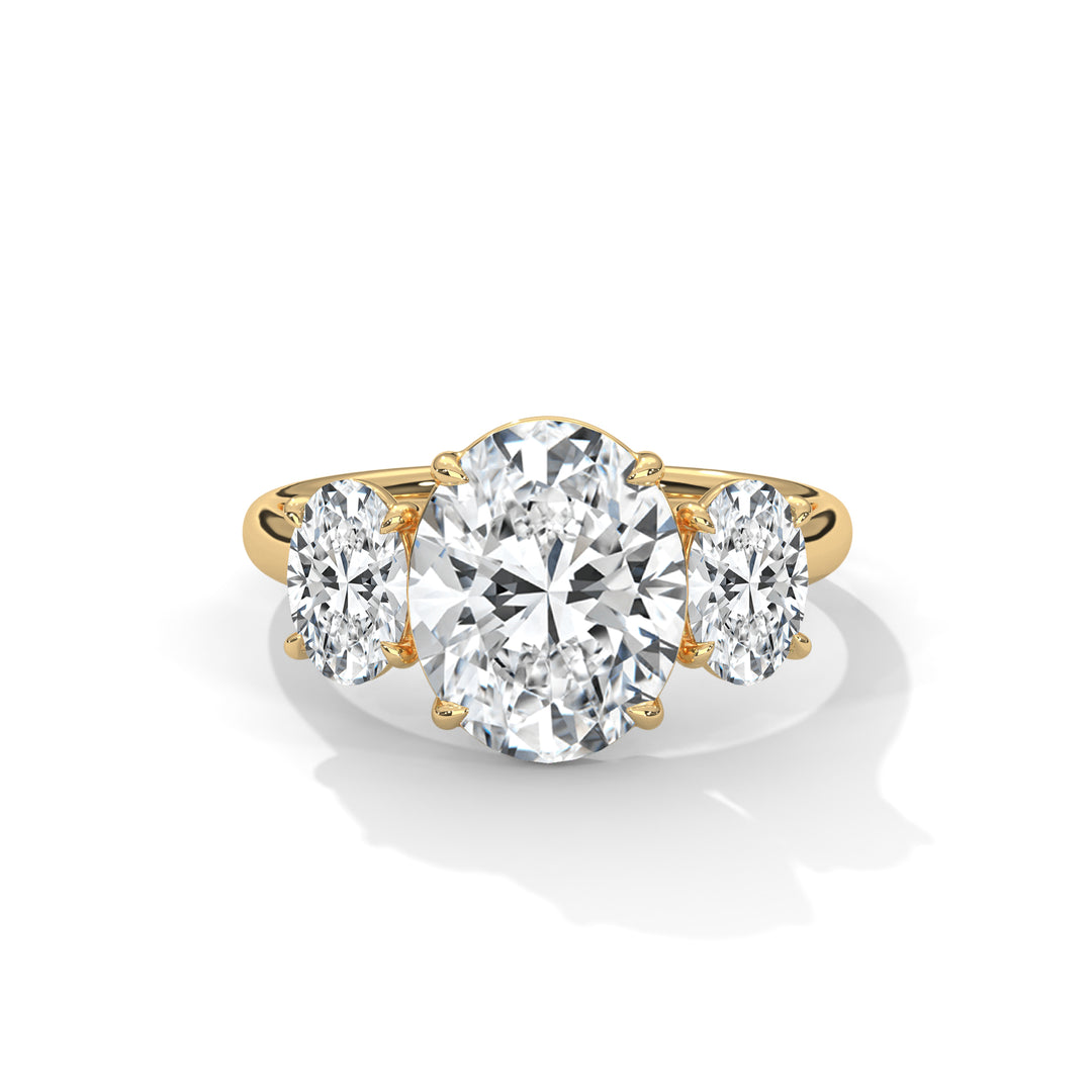 Gold three-stone engagement ring featuring a large oval diamond center flanked by two smaller round diamonds, exuding elegance and brilliance.