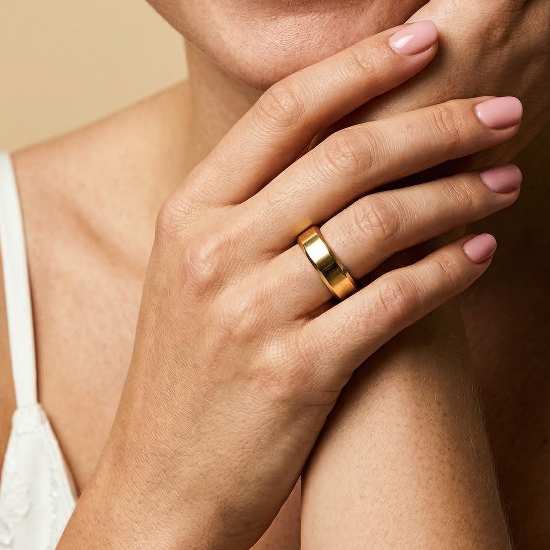 Hand wearing a gold ring on a neutral background