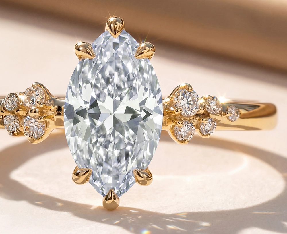 Brilliant marquise-cut diamond solitaire engagement ring set in polished yellow gold featuring cluster accent diamonds on the band, illuminated by soft sunlight.