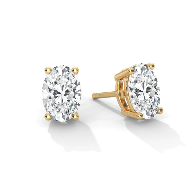 Oval cut diamond stud earrings in gold settings on a white background.