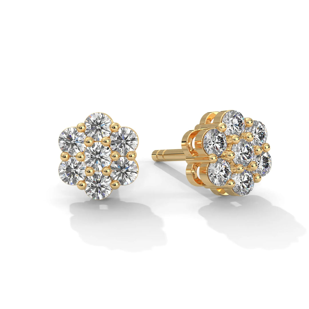 A pair of flower shaped diamond earrings with gold settings on a white background.