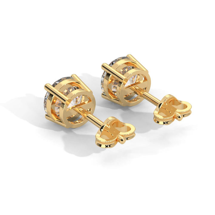 A pair of golden cufflink style earrings with a transparent gemstone.