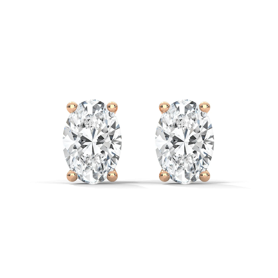 Pair of oval cut diamond earrings with rose gold settings on a white background.