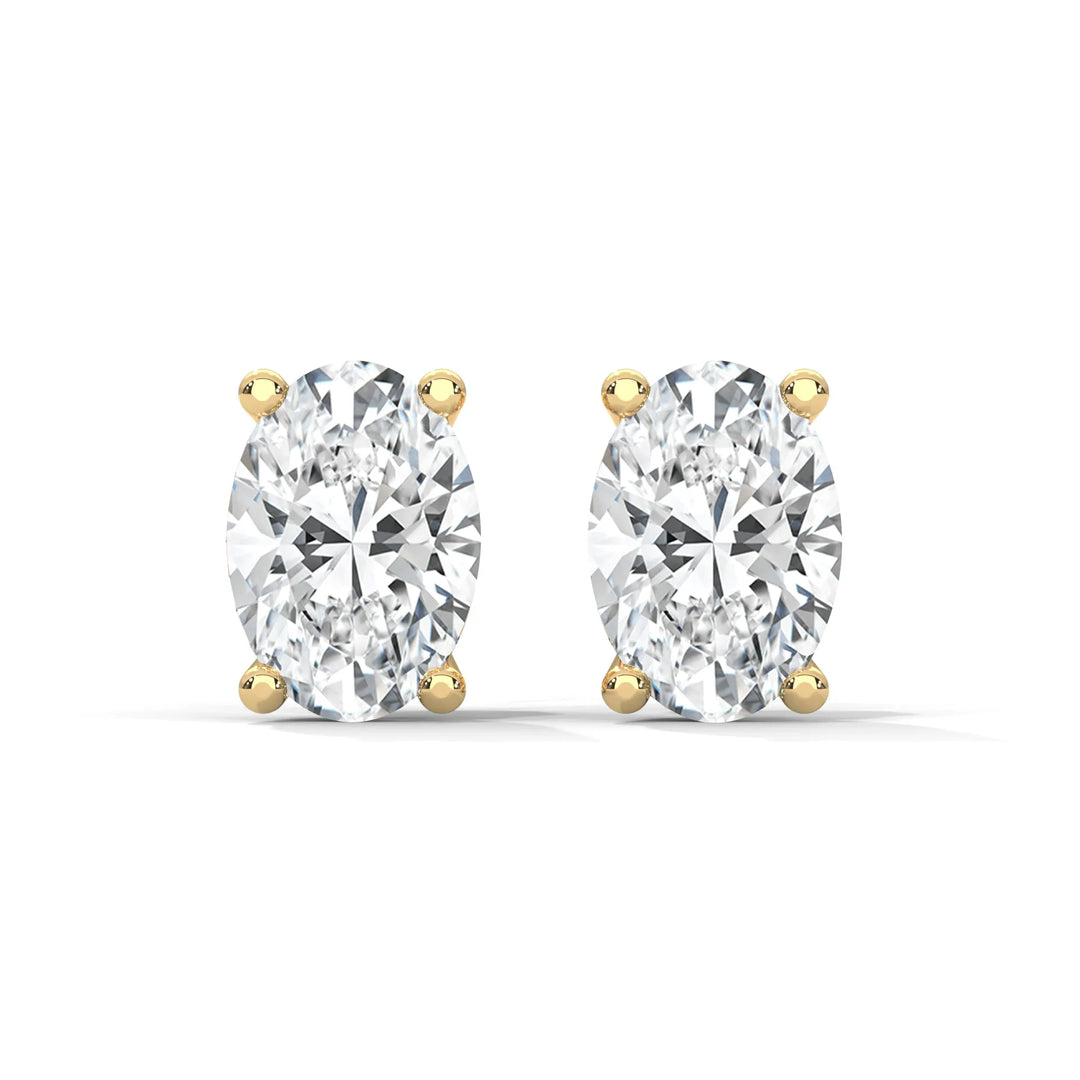 A pair of oval cut diamond stud earrings with gold settings on a white background.